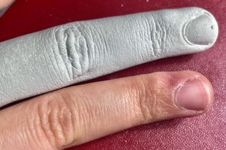 close up of my middle finger next to a pale grey cast of the same finger